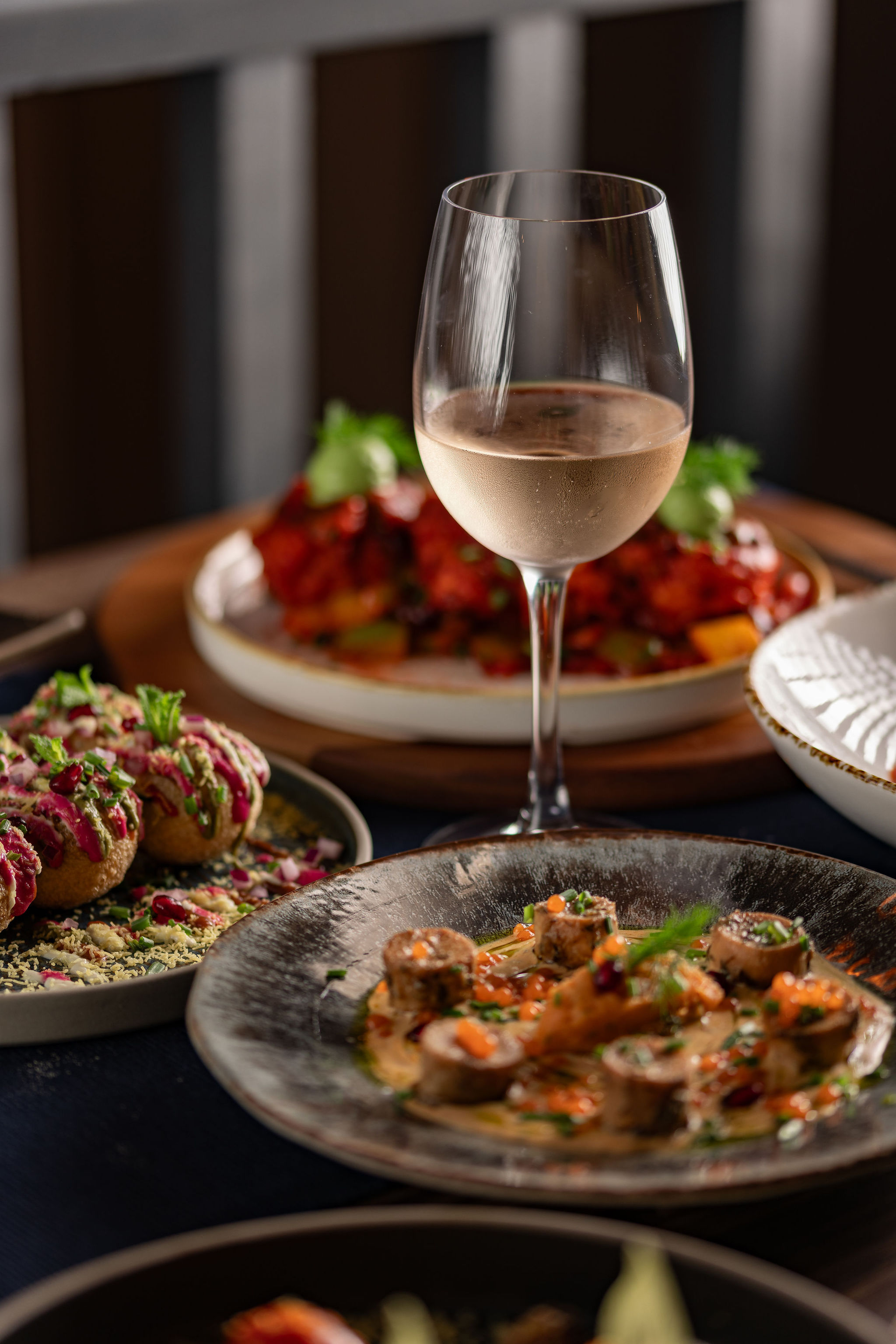 Wine pairing by the glass at Késarum — a glass of rosé alongside a sharing plate of modern Indian cuisine